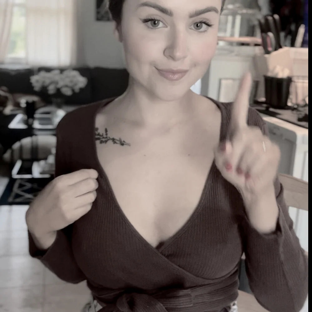 Woman in a brown top pointing upwards in a casual indoor setting